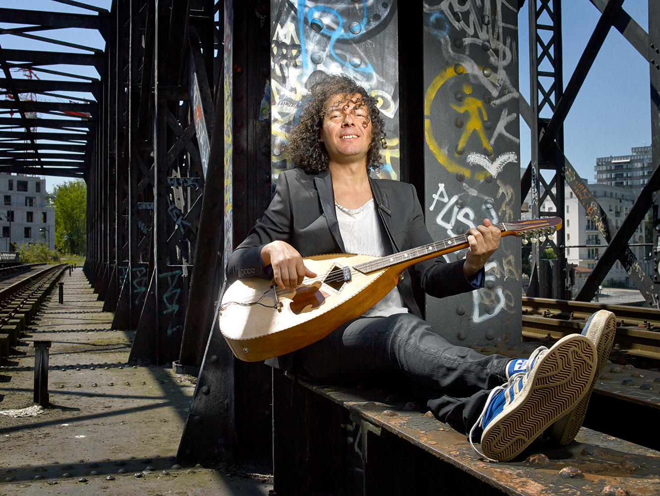  AzizSahmaoui seduto su un ponte con la sua chitarra