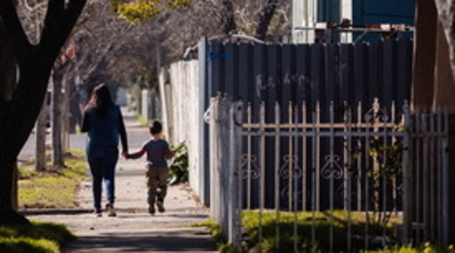 Un genitore che passeggia con il figlio nei pressi della propria abitazione