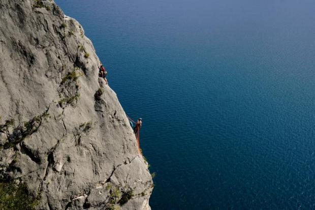 Due alpinisti in cordata su una parete rocciosa a picco sul mare