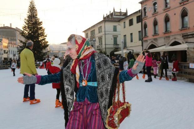 Donna vestita da Befana su una pista di ghiaccio in centro città