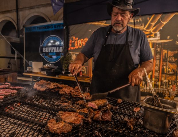 un uomo cucina su un enorme griglia