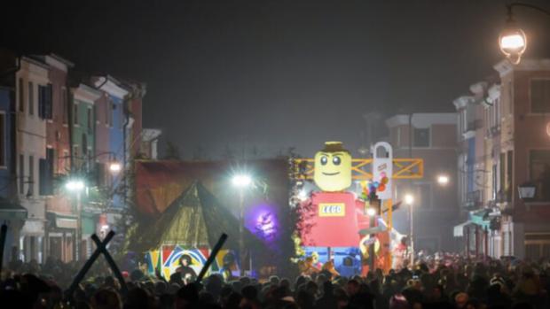 Piazza gremita di pubblico, un palco e, accanto a questo, un omino di lego gonfiabile gigante