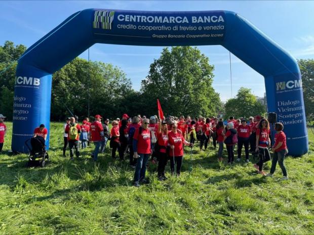 Folto gruppo di persone sotto un arco gonfiabile, su di un prato, alla partenza di una manifestazione podistica