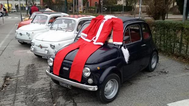 Esposizione di Fiat 500 d'epoca, una delle quali ha un costume da Babbo Natale su cofano e parabrezza