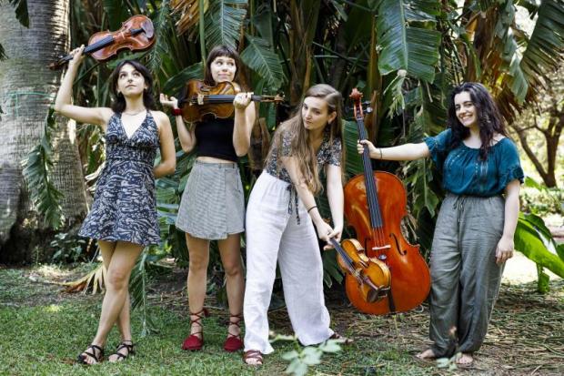 Quattro giovani musiciste in pose buffe con i loro strumenti a corde. Una regge il violino come fosse una mazza da golf