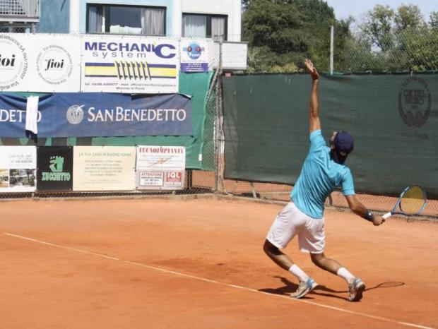 Tennista alla battuta su un campo di terra rossa