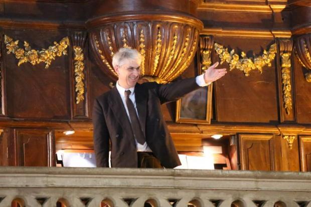 Organista, di fronte al suo strumento, omaggia il pubblico, indicandolo, dopo un suo concerto