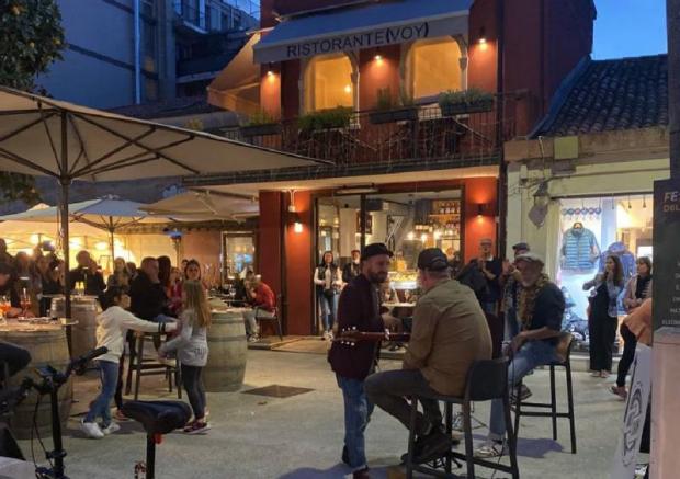 persone sedute ai tavolini in una piazzetta