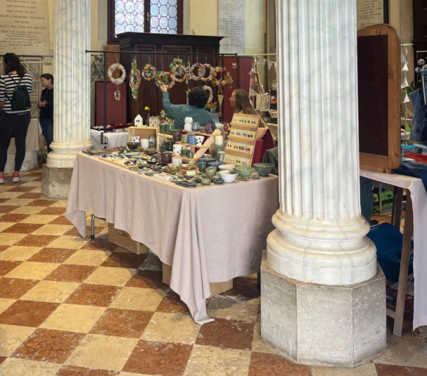 Banchetto di un mercatino allestito tra due colonne in una chiesa