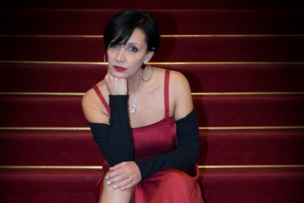 Donna in abito da sera e guanti lunghi seduta su una scalinata con il mento sul pugno destro