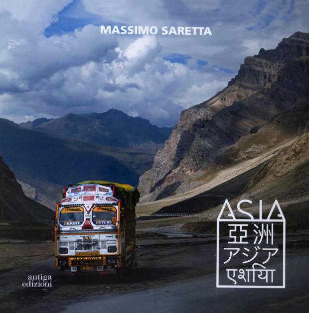 Bus avanza in un paesaggio montano deserto. In basso, logo con titolo della mostra