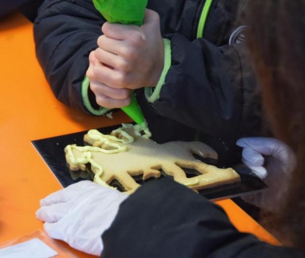 Due mani decorano un San Martino di pasta frolla con una sac à poche