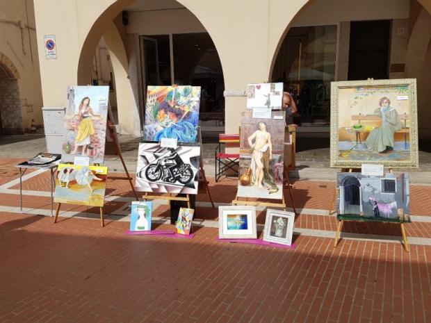 Quadri esposti su cavalletti disposti all'aperto, in una via cittadina