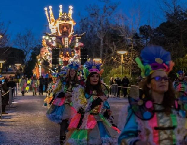 Carro allegorico sullo sfondo, tra la folla; in primo piano tre figuranti in costume