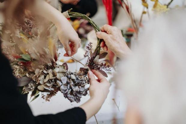 Mani che lavorano a una ghirlanda di fiori